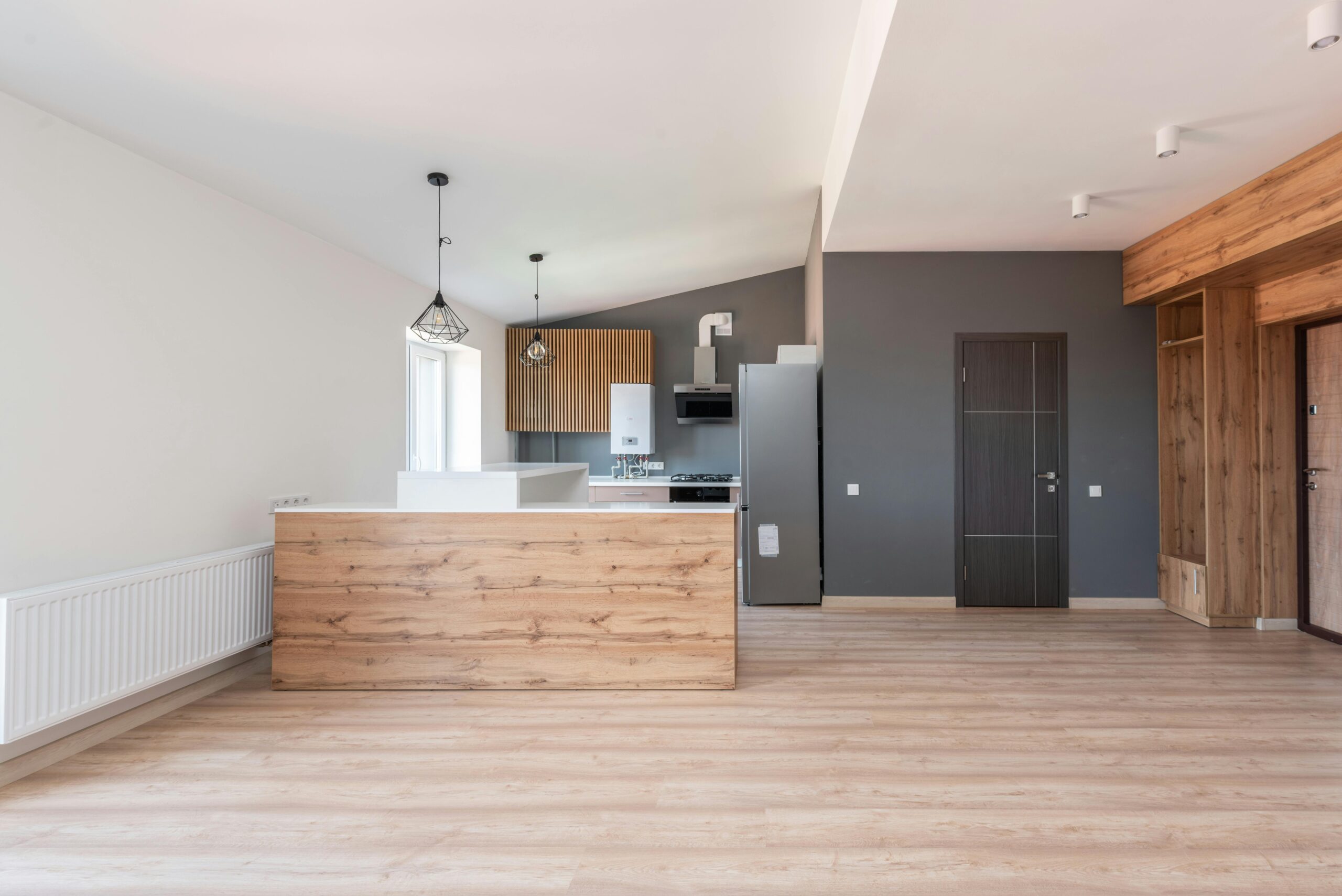 Explore a stylish and minimalistic open-plan kitchen with wood accents and modern design.